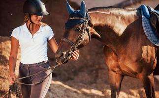 humeur joyeuse. cavalière en uniforme et casque de protection noir avec son cheval photo