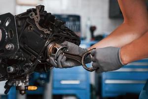 vue rapprochée d'un réparateur professionnel dans un garage qui fonctionne avec un moteur automobile cassé photo