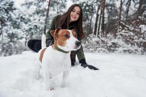 vue rapprochée. brunette souriante s'amusant en marchant avec son chien dans le parc d'hiver photo
