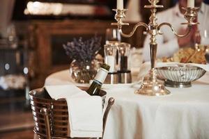 bouteille avec alcool sur le côté. vue rapprochée de la table servie avec une coupe de champagne prête à être célébrée par les visiteurs photo