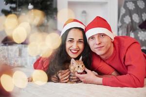 Gens charmants. portrait de couple avec petit chat fête les vacances dans des vêtements du nouvel an photo