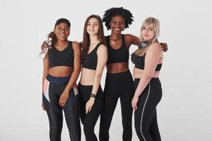 ensemble après l'entraînement. groupe de femmes multiethniques debout dans le studio sur fond blanc photo