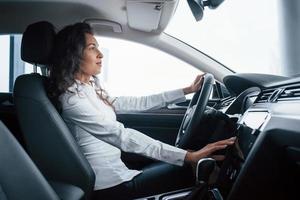 belle femme d'affaires essayant sa nouvelle voiture dans le salon automobile photo