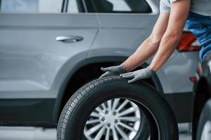 je reviens tout de suite. mécanicien tenant un pneu au garage de réparation. remplacement des pneus d'hiver et d'été photo