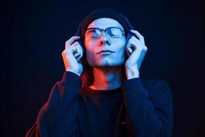 ressens la musique. studio tourné en studio sombre avec néon. portrait d'homme sérieux photo