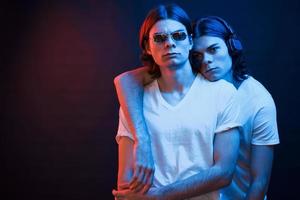étreinte amicale. portrait de frères jumeaux. tourné en studio dans un studio sombre avec néon photo