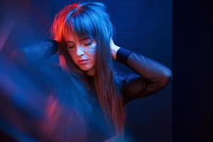 femme magnifique moderne dans le club. studio tourné en studio sombre avec néon. portrait de jeune fille photo