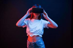 fille impressionnée. jeune femme utilisant des lunettes de réalité virtuelle dans la chambre noire avec éclairage au néon photo