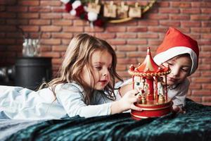 les enfants jouent avec un carrousel de jouets au nouvel an. une fille est avec un bonnet de noel sur la tête photo