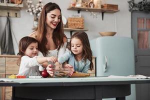 bon appétit. belle jeune femme donne les biscuits alors qu'ils sont assis près de la table avec des jouets photo