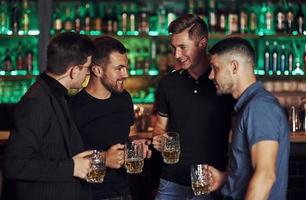 ambiance chaleureuse. amis se reposant dans le pub avec de la bière dans les mains. avoir une conversation photo