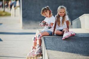 sur la rampe pour les sports extrêmes. deux petites filles avec des patins à roulettes à l'extérieur s'amusent photo