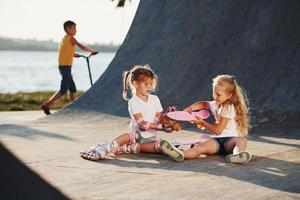 essayer un nouveau patin. deux jolies filles s'amusent dehors dans le parc photo