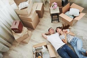 prendre du repos. allongé sur le sol. joyeux jeune couple dans leur nouvel appartement. conception du déménagement photo