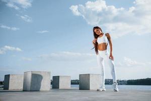 posant pour la caméra. jeune femme de remise en forme avec un type de corps mince est à l'extérieur photo