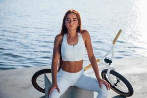 près du vélo. femme de remise en forme se reposant près du lac pendant la journée. belle lumière du soleil photo