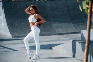 posant pour la caméra. jeune femme de remise en forme avec un type de corps mince est à l'extérieur photo