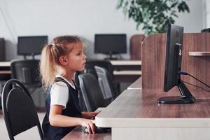 jeune fille assise près de l'ordinateur et à la recherche d'informations photo