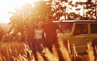 les amis passent un bon week-end à l'extérieur près de leur voiture verte photo