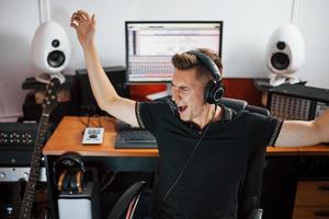 satisfait de la qualité audio. ingénieur du son dans les écouteurs travaillant et mélangeant de la musique à l'intérieur du studio photo