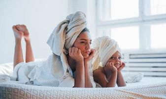 s'amuser. jeune mère avec sa fille a une journée de beauté à l'intérieur dans une salle blanche photo