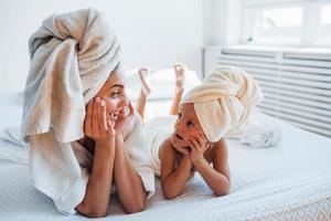 s'amuser. jeune mère avec sa fille a une journée de beauté à l'intérieur dans une salle blanche photo