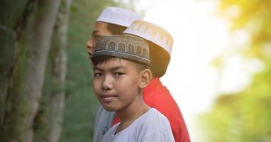 portrait de garçons asiatiques musulmans ou islamiques debout ensemble devant l'arbre et attendant de faire l'activité religieuse à l'école, mise au point douce et sélective. photo