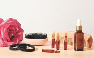 solution de soin des cheveux dans un flacon compte-gouttes et des ampoules, une brosse à peigne et des élastiques à cheveux. traitement du cuir chevelu pour les cheveux faibles et abîmés. photo