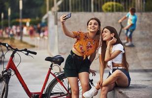 faire un selfie. deux jeunes femmes à vélo passent un bon moment dans le parc