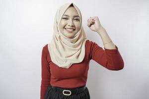 Une jeune femme musulmane asiatique avec une expression réussie heureuse portant un hijab isolé par fond blanc photo