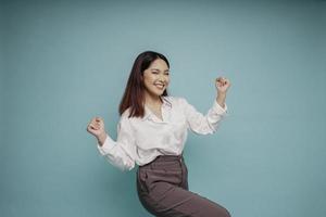 une jeune femme asiatique avec une expression heureuse et réussie portant une chemise blanche isolée par un fond bleu photo