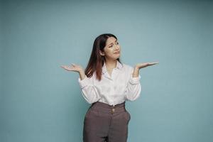 un portrait d'une fille asiatique portant une chemise blanche a l'air si confus entre les choix, isolé par un fond bleu photo