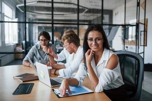 femme brune devant les employés. jeunes gens d'affaires en vêtements formels travaillant au bureau photo