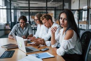 femme brune devant les employés. jeunes gens d'affaires en vêtements formels travaillant au bureau photo