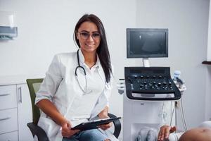 portrait d'un médecin obstétricien assis dans la salle de clinique avec appareil à ultrasons photo