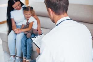 mère avec sa jolie fille visite la clinique. ecouter le medecin photo