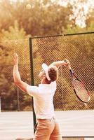 jeune joueur de tennis en vêtements sportifs est sur le terrain à l'extérieur photo