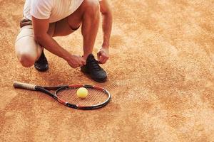 se préparer. jeune joueur de tennis en vêtements sportifs est sur le terrain à l'extérieur photo