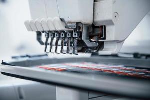 faire des images de fusée. Vue rapprochée de la machine à coudre automatique blanche à l'usine en action photo