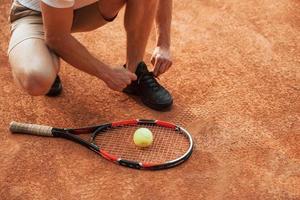 se préparer. jeune joueur de tennis en vêtements sportifs est sur le terrain à l'extérieur photo