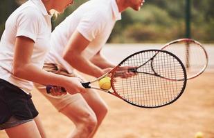 vue de côté. Entraîneur enseignant le jeu de tennis aux étudiantes dans la cour à l'extérieur photo