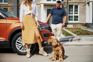 sortant du bâtiment. beau couple se promener avec un chien à l'extérieur près de la voiture photo