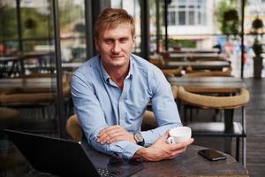 vue de face du gars qui est dans un café moderne avec son ordinateur portable pendant la journée photo