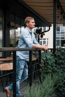 s'appuyant sur les balustrades. vue de face d'un gars en jeans qui se tient dans le café pendant la journée photo