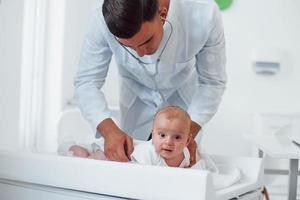 le jeune pédiatre est avec un petit bébé à la clinique pendant la journée photo