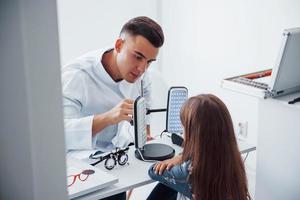 deux panneaux sur la table. le jeune ophtalmologiste est avec une petite visiteuse à la clinique photo