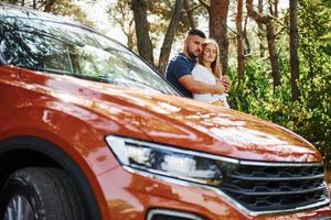 couple s'embrassant dans la forêt près d'une voiture moderne photo