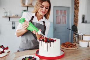 verser de la crème. femme se tient à l'intérieur dans la cuisine avec une tarte maison photo