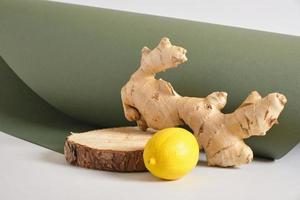 racine de gingembre, citron et support en bois sur fond gris et vert photo