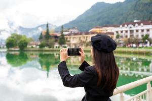 jeune femme prenant une photo au lac sapa avec réflexion et ciel bleu dans la province de lao cai, vietnam